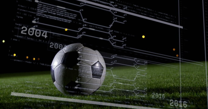 Resting soccer ball displaying digital data overlay on grass turf at night, with code metrics