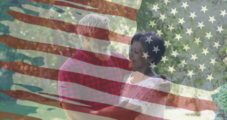 Embracing couple wearing white top and red plaid shirt in garden, with American flag overlay