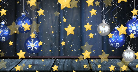 Naklejka premium Hanging blue-silver baubles and golden stars from silver ribbons above wooden floor, navy curtain