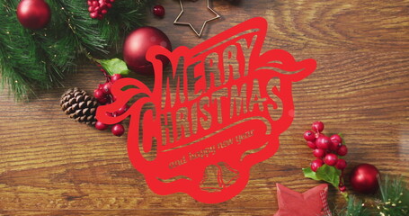 Displaying red sign reading Merry Christmas and happy new year on wooden tabletop, with pine cones