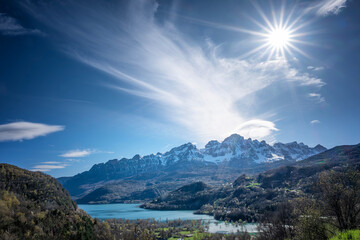sun shining over Bubal reservoir, in Pueyo de Jaca with the snow-capped Pena Telera in the background, Pyrenean landscape in the Tena Valley in the Aragonese Pyrenees