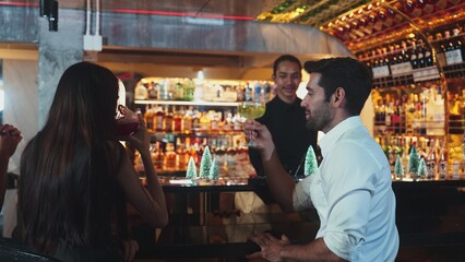 Cheers of group friend drinking special Midori Sour and punch cocktail with candy cane at luxurious counter bar in christmas tree neon snow festive theme, warmly friendship couple nightlife. Vinosity.