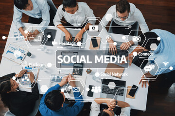 A diverse group of professionals collaborates over laptops in a modern office, surrounded by social media icons, showcasing teamwork and digital communication in business. Amity