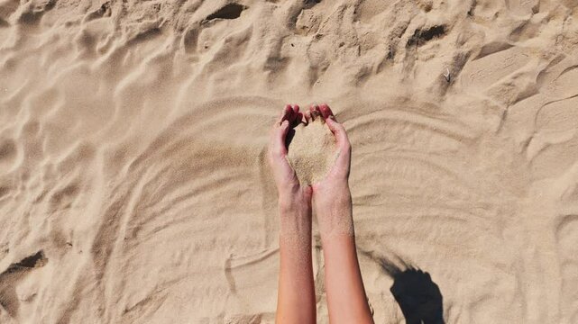 Beach sand scattered by female hands. Top view against sand background