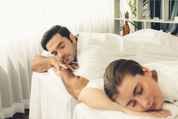 Caucasian couple customer enjoying relaxing anti-stress spa massage and pampering with beauty skin recreation leisure in day light ambient salon spa at luxury resort or hotel. Quiescent