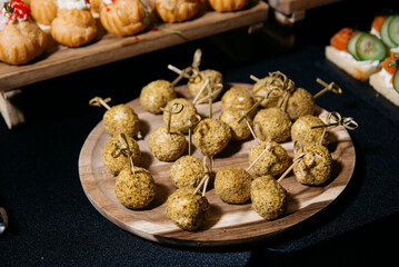 Pistachio-Crusted Cheese Balls on Skewers. Appetizing display of bite-sized cheese balls coated in crushed pistachios and served on wooden picks, perfect for catering or parties.