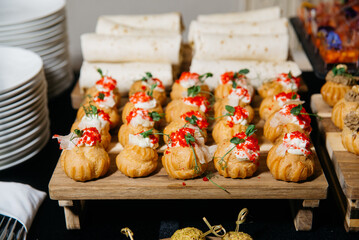 Savory Cream Puffs with Red Caviar Topping. Elegant party canapés featuring golden cream puffs filled with savory mousse and topped with red caviar and microgreens.