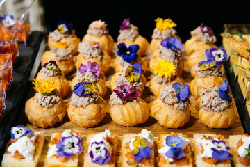Gourmet savory puffs with edible flowers. Elegant puff pastry bites filled with meat mousse and...