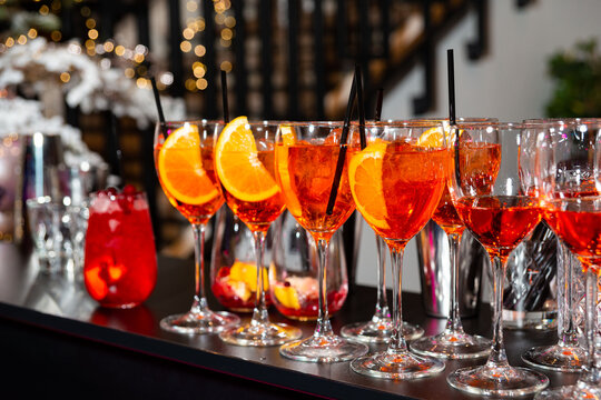 Aperol Spritz Cocktails on Festive Bar Counter. Multiple Aperol Spritz cocktails with orange slices arranged on a bar counter, ready for a party or celebration.