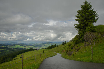 Scenic winding road through green hills under a cloudy sky in a mountainous region