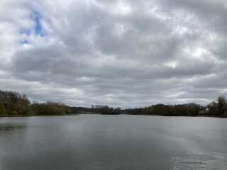 Mesmerizing view of a calm lake surrounded by trees under a cloudy sky