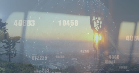 Projecting digital network globe across skyline with pine tree through window, with dreamcatcher