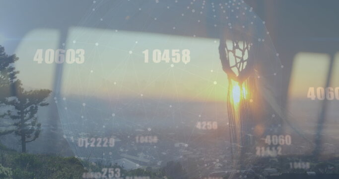 Projecting digital network globe across skyline with pine tree through window, with dreamcatcher
