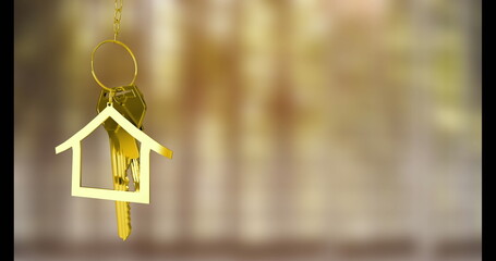 Dangling gold house-shaped keyring on gold chain with metal keys against warm backdrop, copy space