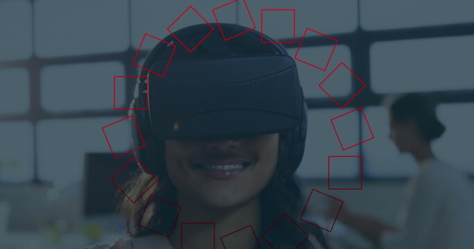 Smiling woman wearing virtual reality headset exploring virtual environment in open office space