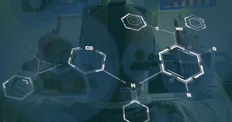 Reviewing researcher wearing headphones examining molecular chemistry overlay on computer monitor