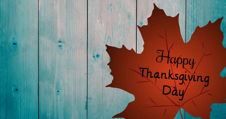 Fototapeta premium Showing brown maple leaf silhouette displaying Happy Thanksgiving Day text on teal wall, copy space