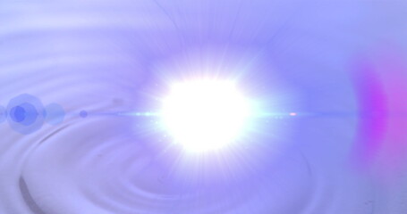 Emitting white light flare centered over rippled water surface in studio with lens flare halos
