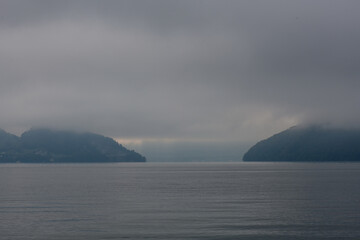 Fog envelops serene mountain landscape over tranquil water at dawn
