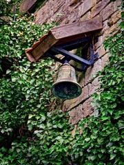 Old historic bell hanging on an ivy covered wall