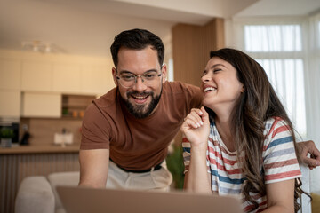 Happy couple watching funny videos on laptop at home