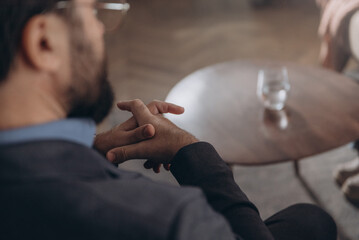 Close up of male psychologist listens to patient in therapy room