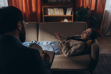 Nervous woman shares emotions gesturing with hands while lying on couch in therapy room