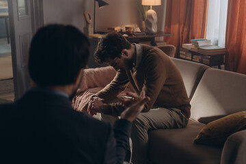 Guy sits on couch with contemplative expression during therapy session