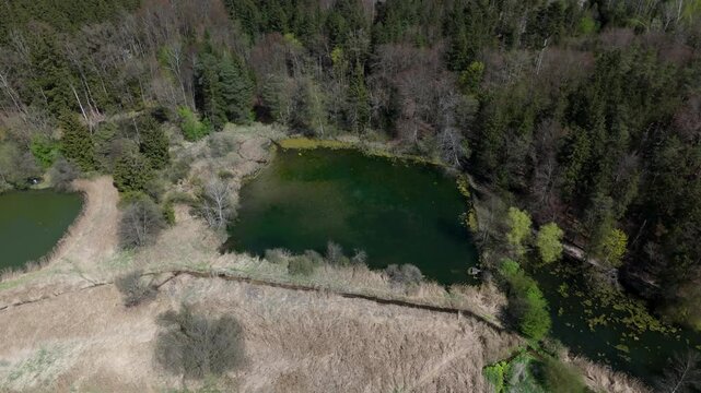 Drone shot of Spiegelweiher, fish pond chain in Grafing bei Muenchen, Bavaria, Germany. This hidden gem near Munich features quiet hiking trails, reflective waters and vibrant spring greenery. 