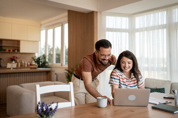 Couple working from home using laptop and smiling at the screen