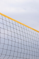 Beach volleyball net close-up. Fragment of a volleyball net on the beach against a cloudy sky....