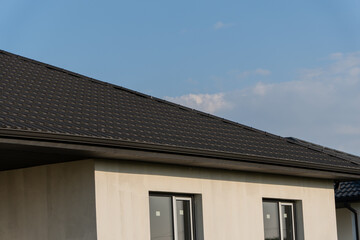 A newly installed roof on a contemporary home is shown against a clear blue sky, highlighting its sleek design and architecture
