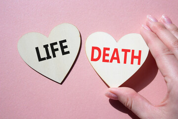 Life or Death symbol. Concept word Life or Death on wooden hearts. Businessman hand. Beautiful pink...