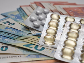 Closeup shot of a pile of Euro banknotes and medical pills
