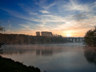 Fototapeta premium Lake with a bridge in the background at sunrise