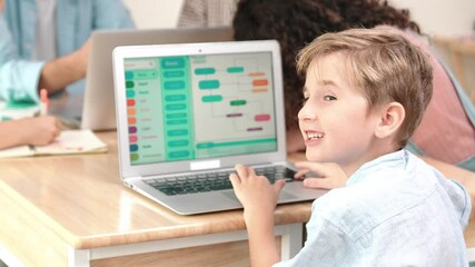 Smart caucasian boy turn around and looking at camera in STEM technology class while group of diverse student and teacher doing mind mapping. Smart child learning coding software program. Pedagogy. - Powered by Adobe