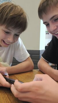 High school students teens gen z two gue, friends playing online video game e-sport play diverse gadgets. Guys playing on the phone.