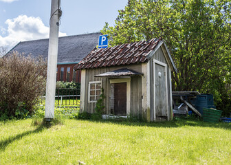 Small weathered wooden playhouse in sunny yard.