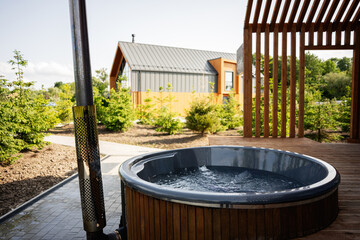 Outdoor garden hot tub with modern house and green surroundings during summer
