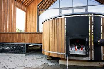 Wooden outdoor hot tub with stove in modern backyard setting