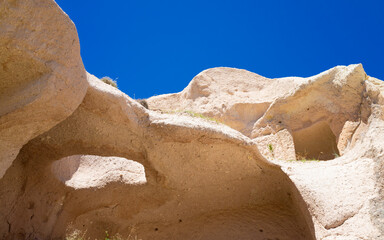 Unique rock formations and carved caves in soft volcanic tuff located in Cappadocia, Turkey. Natural erosion and sunlight reveal geological textures typical for Cappadocia region.