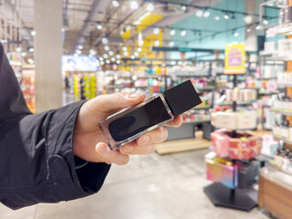 Man buying make up at cosmetics section in store. choosing cosmetics, perfumes, creams and shampoos, Using tester.
