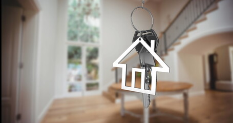 Dangling metallic key ring with house-shaped key fob and keys in entry hall with curved staircase
