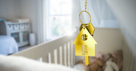 Hanging gold house-shaped keychain from short chain in softly lit nursery, with metal key near crib
