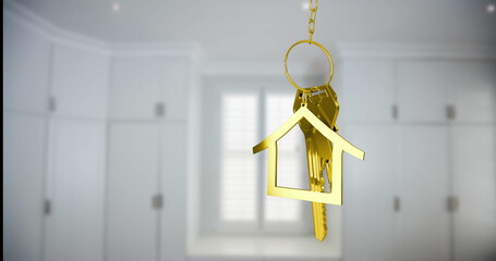 Hanging gold house-shaped keychain swinging gently in kitchen entryway, with metal keys and chain