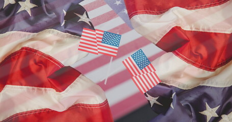 Fototapeta premium Displaying two miniature American flag picks standing on tabletop, with crumpled flag backdrop