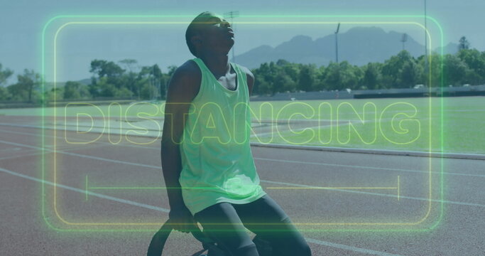 Fototapeta Sitting teen wearing neon green top breathing on ring at track beside turf, with DISTANCING overlay