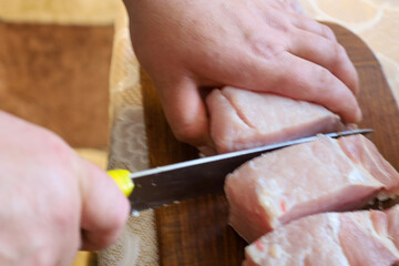 Obraz premium Hands are cutting fresh meat on a wooden board, reflecting the preparation process for cooking. This shot focuses on culinary actions and ingredients for a future dish.