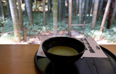 Matcha green tea in a traditional japanese tea ceremony setting overlooking bamboo forest