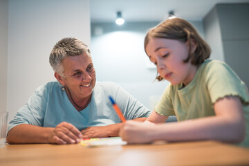A portrait of grandmother and granddaughter doing homework together at home.	
